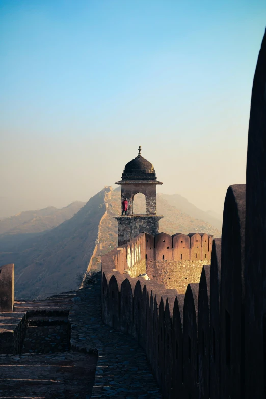 a clock tower sitting on top of a stone wall, inspired by Steve McCurry, pexels contest winner, pagodas on hills, mogul khan, cannons, late afternoon light