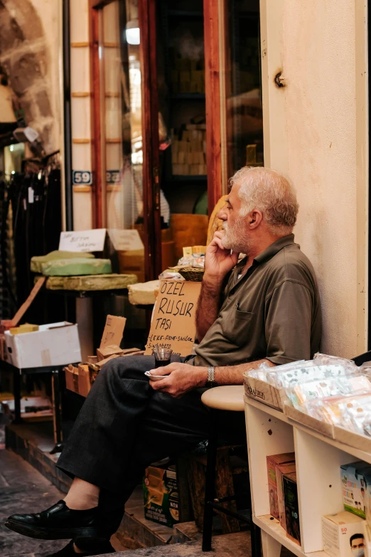 a man sitting on a bench talking on a cell phone, a photo, pexels contest winner, renaissance, old shops, australian, hide the pain harold, israel