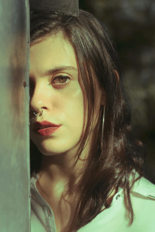 a woman in a white shirt leaning against a wall, an album cover, inspired by Elsa Bleda, pexels contest winner, intricate heterochromia sad, portrait of normal teenage girl, cynthwave, headshot