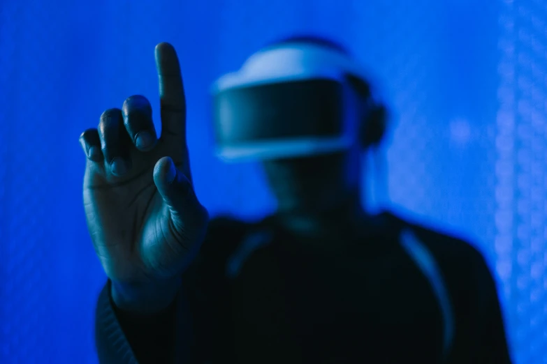a person wearing a virtual reality headset in front of a blue background, by Adam Marczyński, unsplash, finger, in a cyberpunk themed room, instagram post, dramatic white and blue lighting