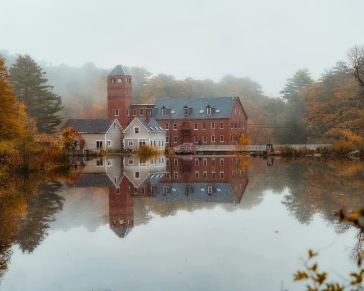 a large red brick building sitting on top of a lake, pexels contest winner, tonalism, mill, new england architecture, beauty fog, subtle colors