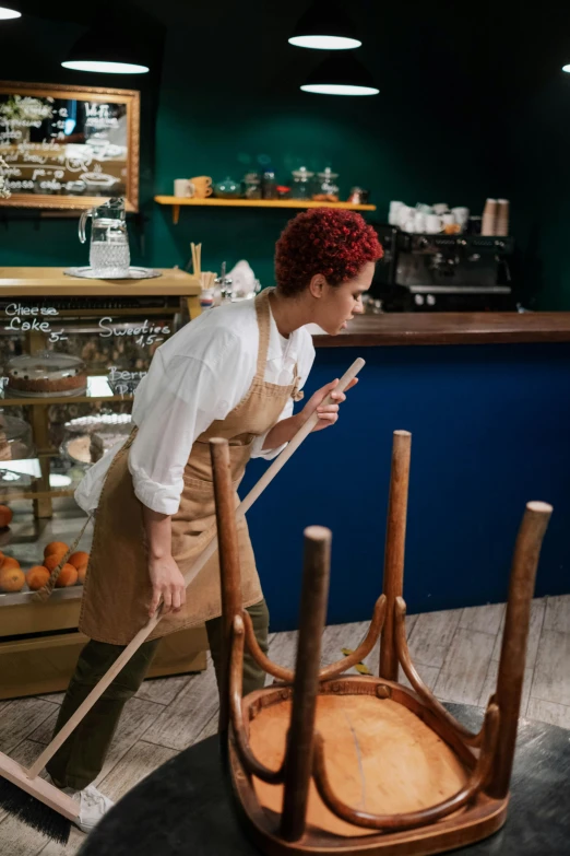 a woman sweeping the floor with a broom, by Andries Stock, pexels contest winner, process art, cute bakery shop, aussie baristas, stanchions, inspect in inventory image