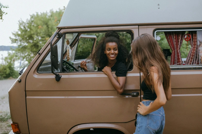 two women looking out the window of a van, pexels contest winner, renaissance, brown skinned, cheeky smile, 1970s style, stained antique copper car paint