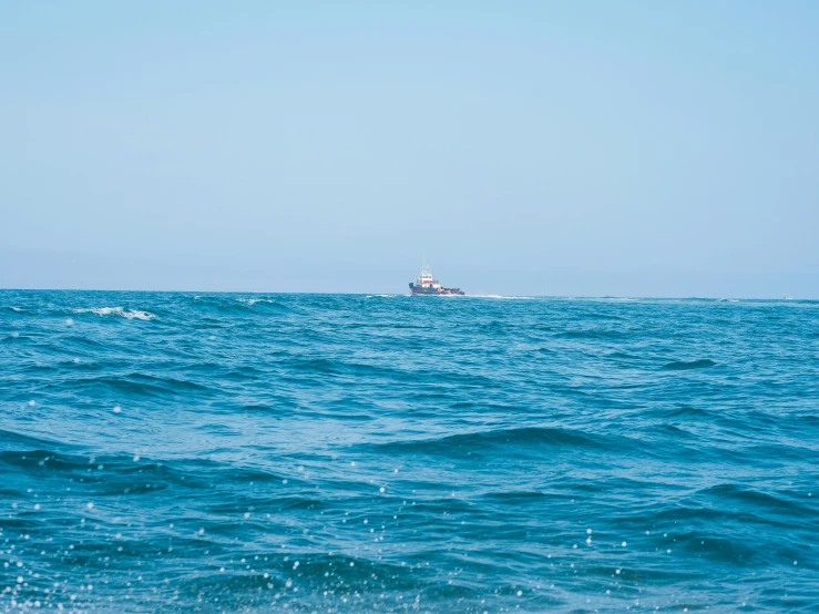 a large body of water with a boat in the distance, an album cover, unsplash, blue ocean, 2 5 6 x 2 5 6 pixels, ship, offshore winds