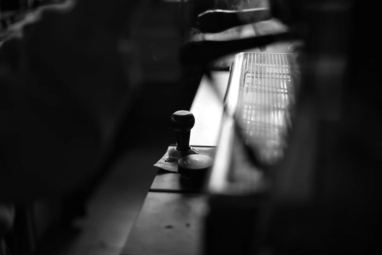 a black and white photo of a person sitting on a bench, by Mathias Kollros, unsplash, ancient coffee machine, rubber stamp, glare, knobs