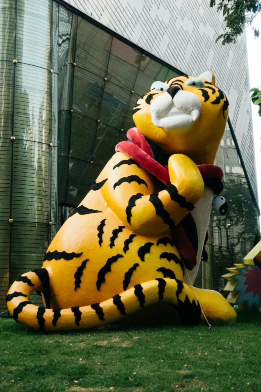 a large tiger statue sitting on top of a lush green field, a cartoon, graffiti, bangkok townsquare, ((tiger)), big bee, feng zhu |