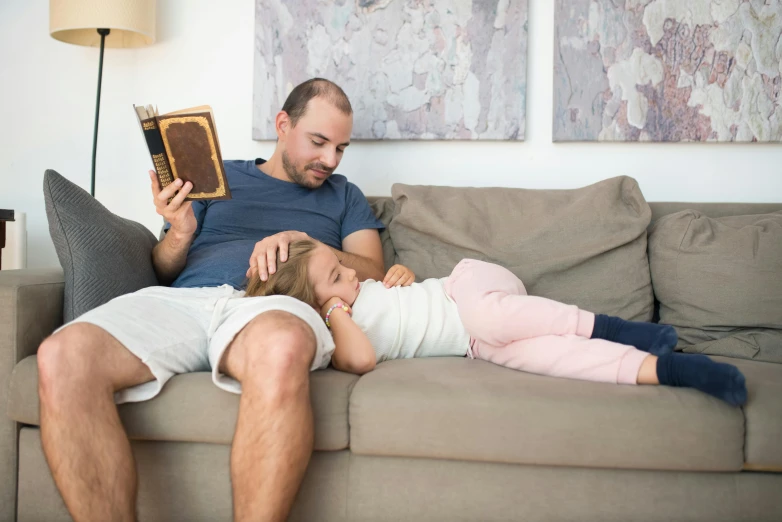 a man reading a book to a little girl on a couch, pexels contest winner, figuration libre, “ iron bark, relaxed pose, press shot, high quality photo