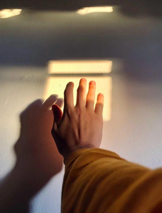 a person holding a remote control in their hand, an album cover, inspired by Elsa Bleda, trending on pexels, light and space, window lighting, ( ray of sunlight ), hands straight down, bisexual lighting