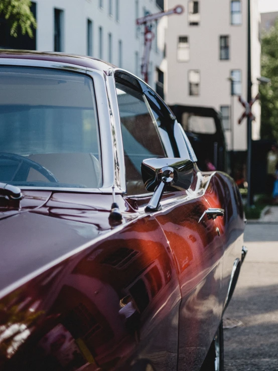 a red car parked on the side of the road, by Adam Rex, pexels contest winner, photorealism, 1 9 7 0 s car window closeup, maroon metallic accents, with sleek lines and a powerful, in a city with a rich history