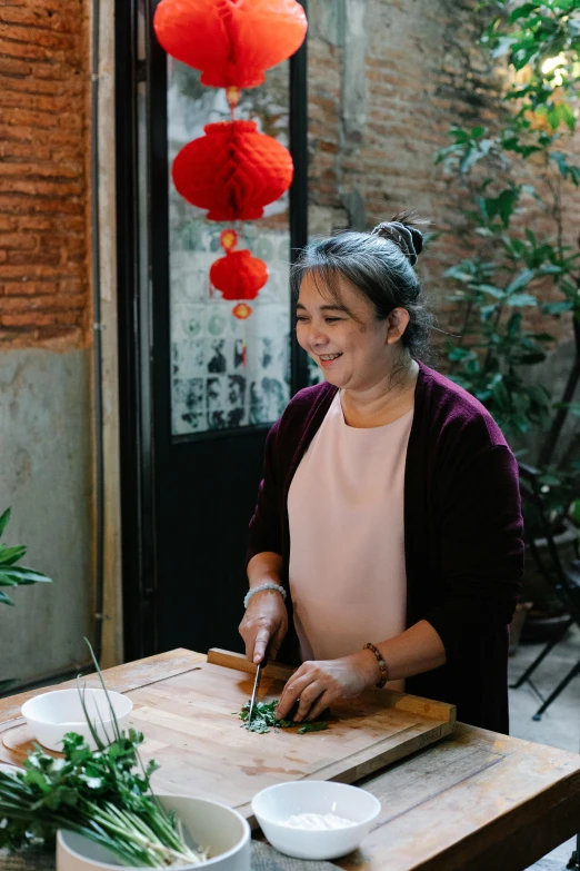 a woman cutting vegetables on a cutting board, inspired by Cui Bai, happening, standing in a restaurant, with paper lanterns, bao phan, portrait image