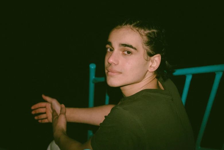 a close up of a person holding a tennis racket, an album cover, by Elsa Bleda, thick bushy straight eyebrows, he is wearing a black t-shirt, sitting down, portrait androgynous girl