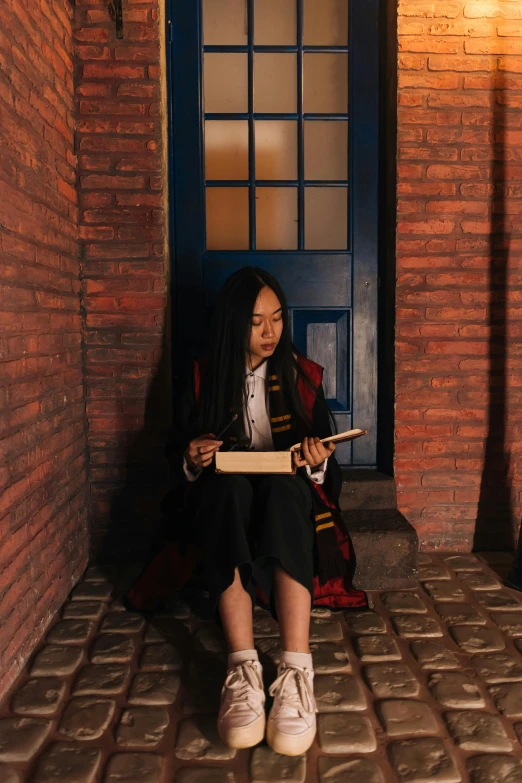 a woman sitting on a brick floor holding a skateboard, an album cover, by Julia Pishtar, pexels contest winner, magical realism, wearing hogwarts!!! robes!!!, young asian girl, located in a wizard's shop, magical school student uniform