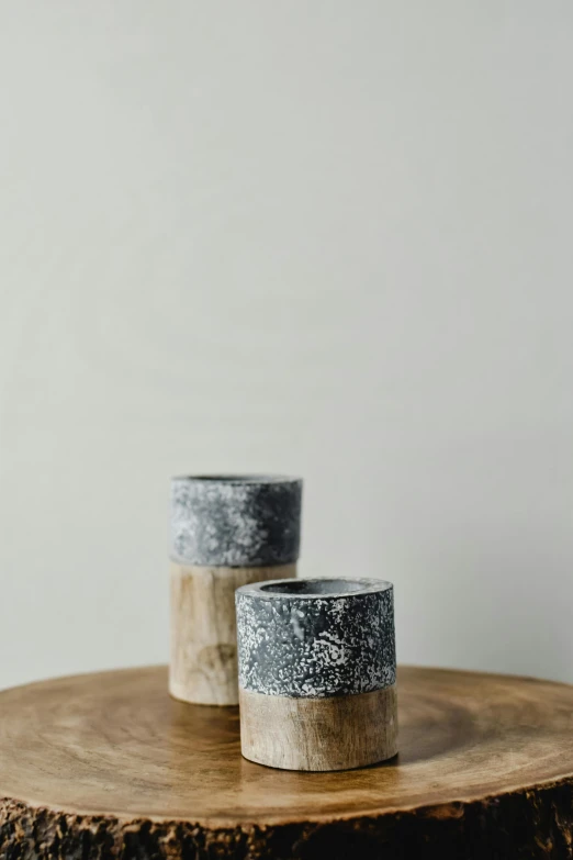 a couple of cups sitting on top of a wooden table, a picture, textured base ; product photos, weathered concrete, o'neill cylinder colony, medium