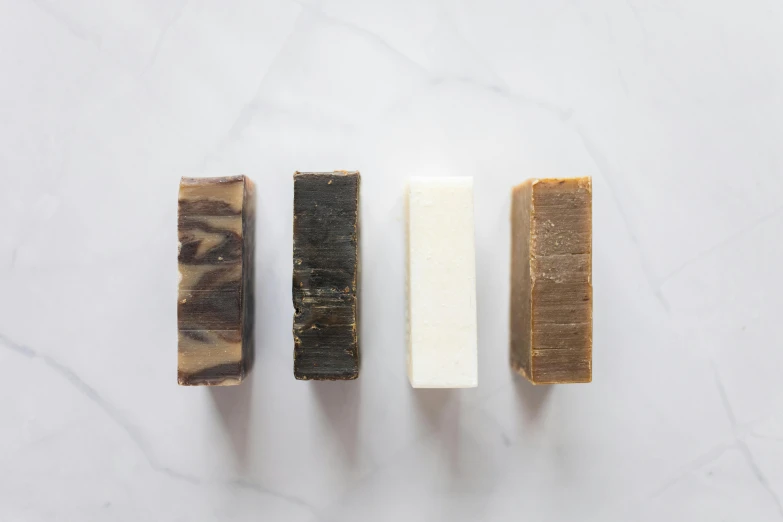 three bars of soap sitting next to each other, by Jessie Algie, carbon black and antique gold, browns and whites, birdseye view, dezeen