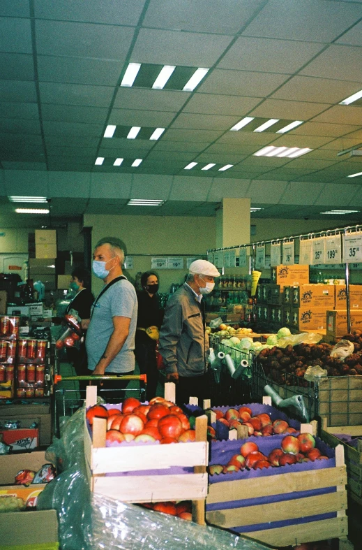 a couple of people that are standing in a store, fruit, people are wearing masks, located in hajibektash complex, taken on a 2000s camera