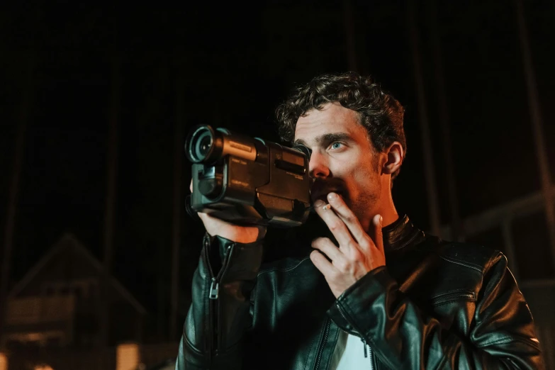 a man in a leather jacket holding a video camera, by Nick Fudge, pexels contest winner, night vision, robert sheehan, performance, tom of finland