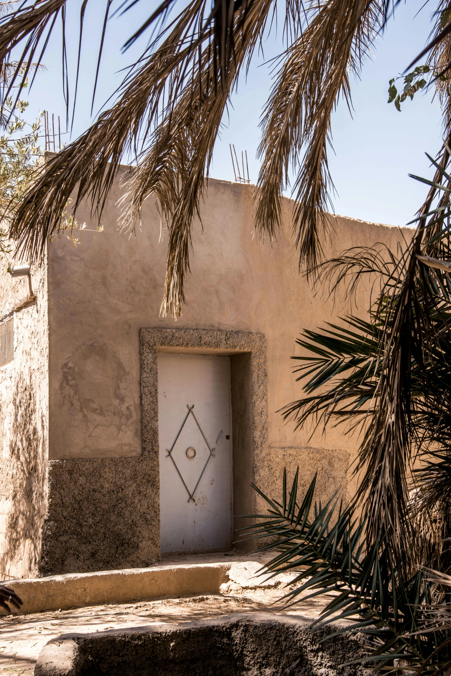 a white door sitting on the side of a building, inspired by Riad Beyrouti, les nabis, arid mountains and palm forest, grey, rustic, located in hajibektash complex