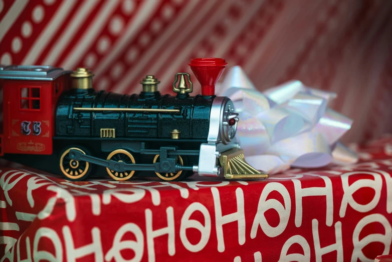 a toy train sitting on top of a christmas present, by Julia Pishtar, fan favorite, navy, hasbro, closeup