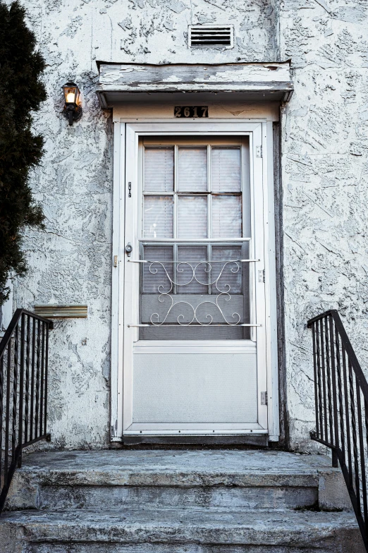 a white door sitting on the side of a building, by Washington Allston, unsplash, folk art, silver，ivory, iron railing, slate, an intruder