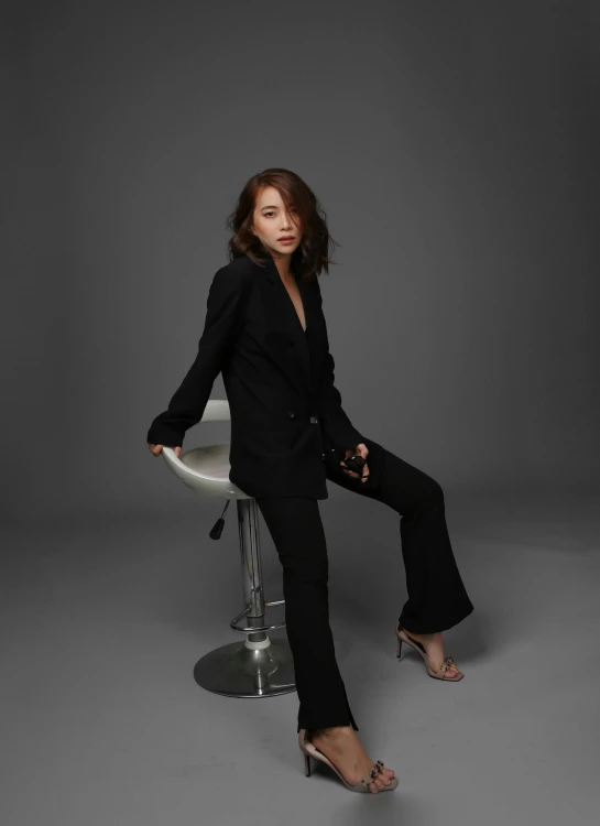 a woman sitting on top of a stool, an album cover, inspired by Feng Zhu, unsplash, wearing causal black suits, actress, profile image, hana alisa omer