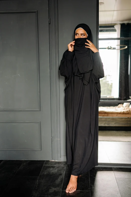 a woman in a black hijab talking on a cell phone, wearing nanotech honeycomb robe, full body-n 9, dress in voile, black