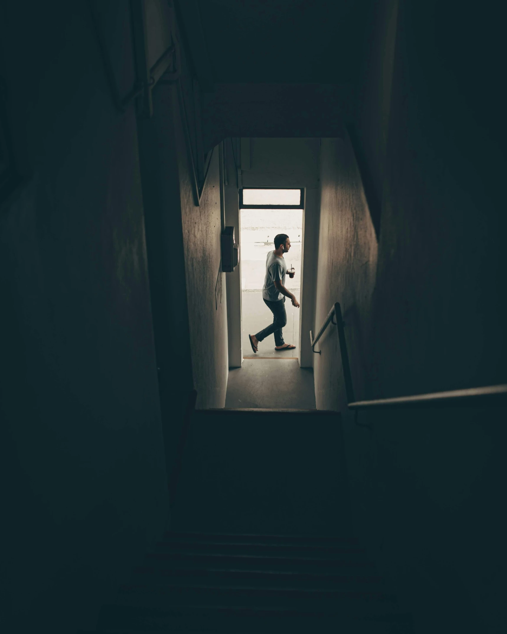 a man walking up a flight of stairs in a dark room, inspired by Elsa Bleda, unsplash contest winner, happening, hung above the door, walking boy, in a white room, non-binary