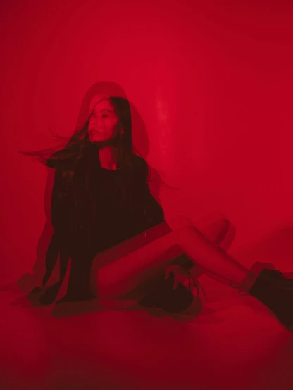 a woman sitting on top of a bed under a red light, an album cover, ariana grande photography, profile image, red boots, lily frank