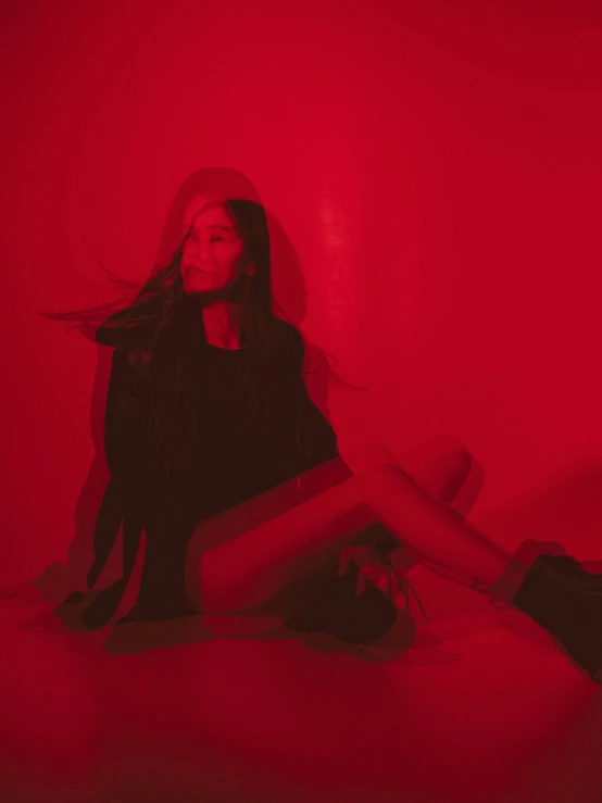 a woman sitting on top of a bed under a red light, an album cover, ariana grande photography, profile image, red boots, lily frank