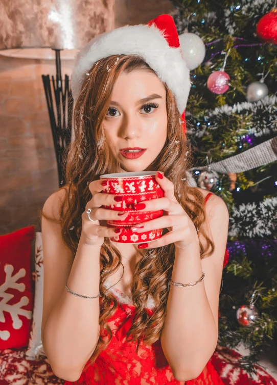 a woman holding a cup in front of a christmas tree, a portrait, by Julia Pishtar, pexels contest winner, young beautiful amouranth, hot cocoa drink, avatar image, santa's workshop