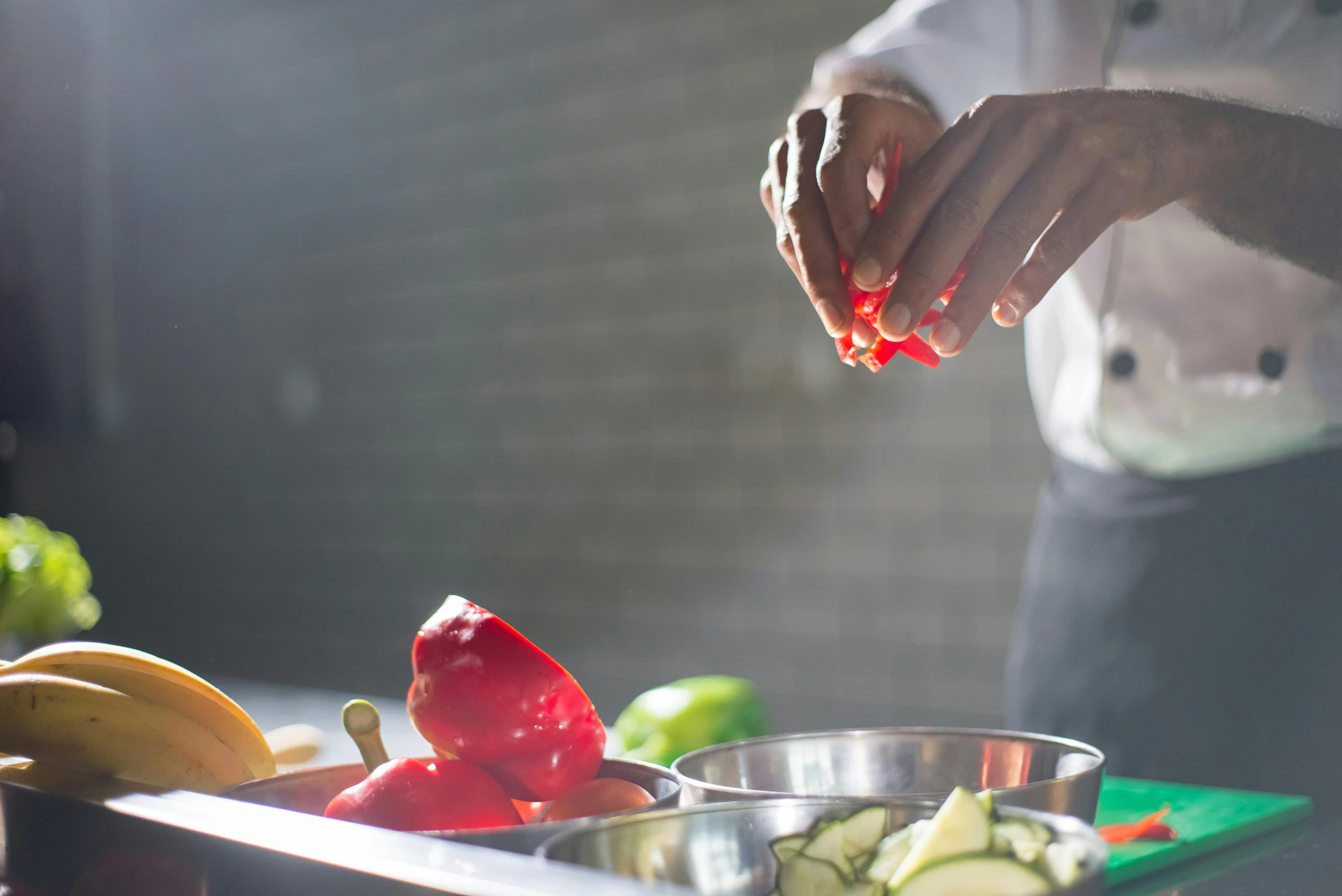 a person in a kitchen preparing food on a cutting board, even lighting, vibrant red and green colours, avatar image, stainless steel