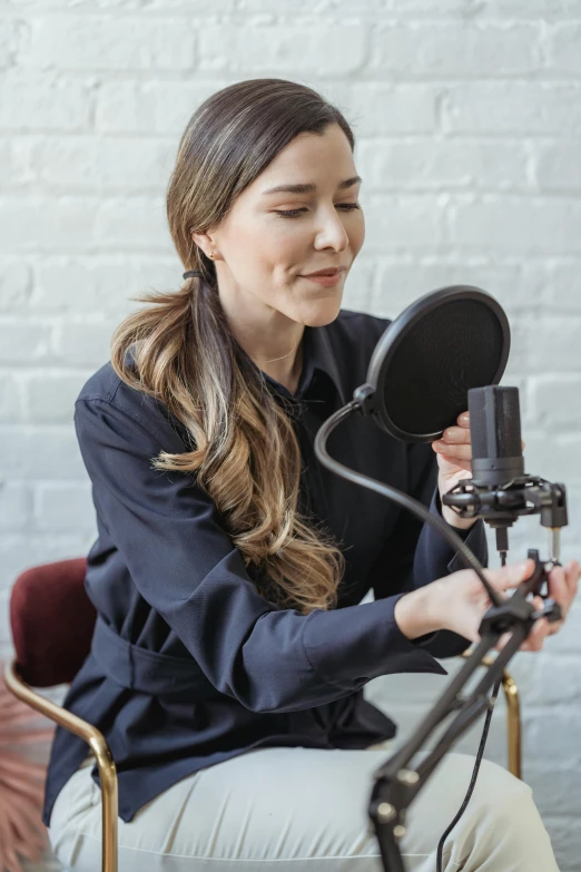 a woman sitting in front of a microphone, studio quality product, multiple stories, features, instagram post