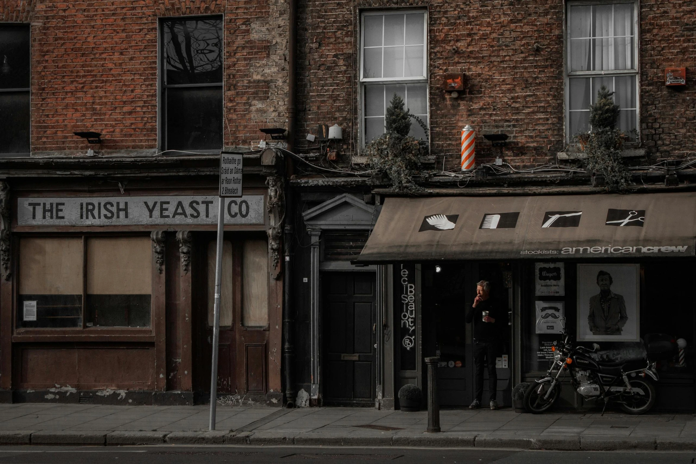 a motorcycle parked in front of a brick building, by Kevin Connor, unsplash contest winner, visual art, old shops, yeast, lush vista, outside a saloon