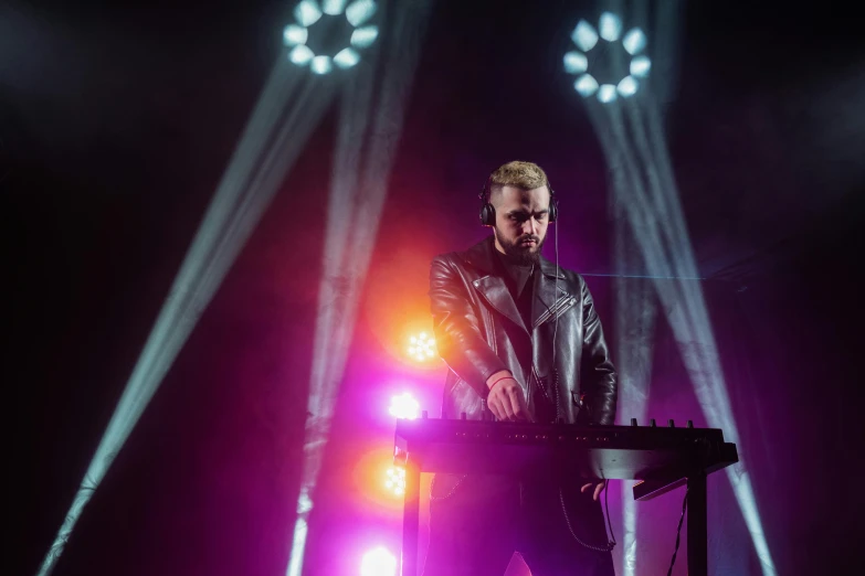 a man that is standing in front of a keyboard, by Matt Cavotta, pretty lights, wearing studded leather, stage photography, square