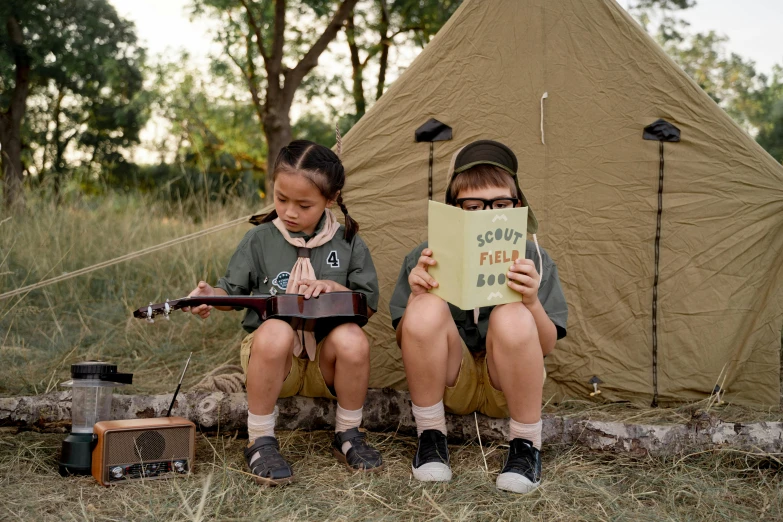 a couple of kids sitting next to each other in front of a tent, an album cover, by Emma Andijewska, pexels contest winner, boy scout troop, ukulele, cardboard, 15081959 21121991 01012000 4k