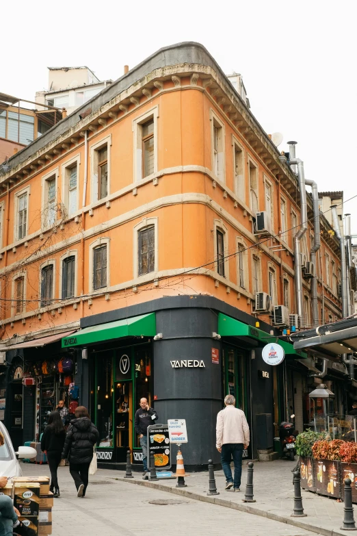 a group of people walking down a street next to tall buildings, olive garden, istanbul, shop front, black and terracotta