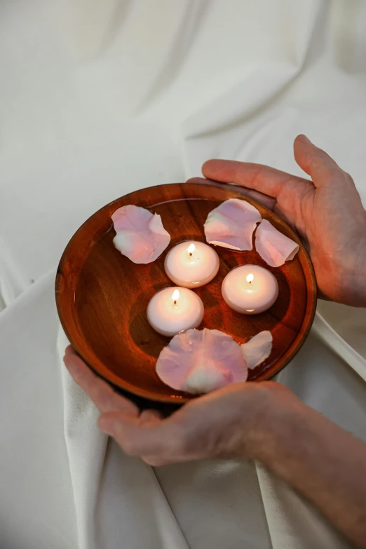 a person holding a bowl with candles in it, rose petals, soft pads, soft shapes, uplit