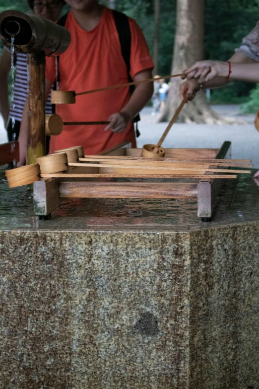 a group of people standing around a table, by Joel Shapiro, kinetic art, laos, barbecue, churning, mill