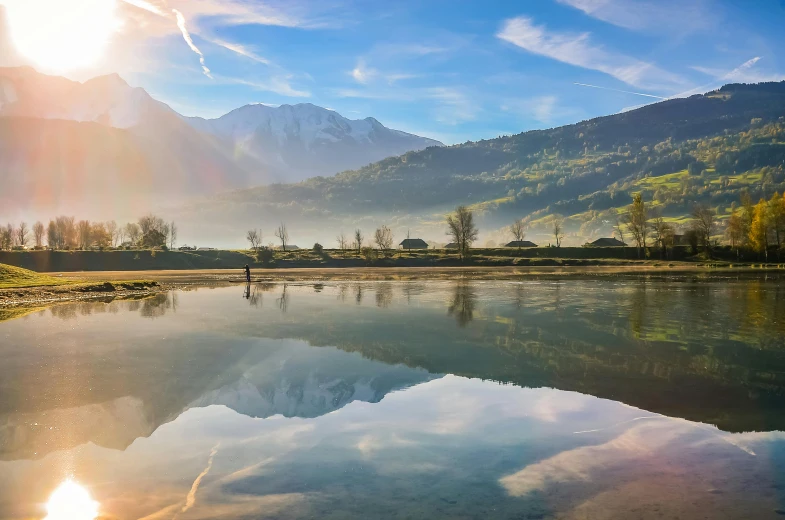 a body of water with mountains in the background, a picture, by Julia Pishtar, pexels contest winner, chamonix, reflection puddles, fishing, sunny morning light