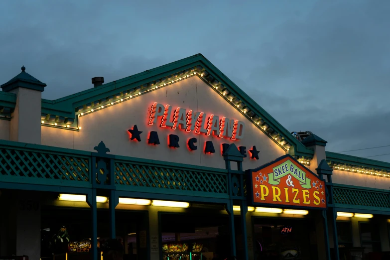 the exterior of a restaurant lit up at night, by Robert Sivell, pexels contest winner, arcade game, seaside, caulfield, regal