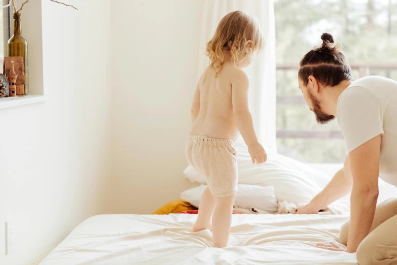 a little girl standing on top of a bed next to a man, pexels contest winner, figuration libre, walking boy, third trimester, australian, wearing only pants