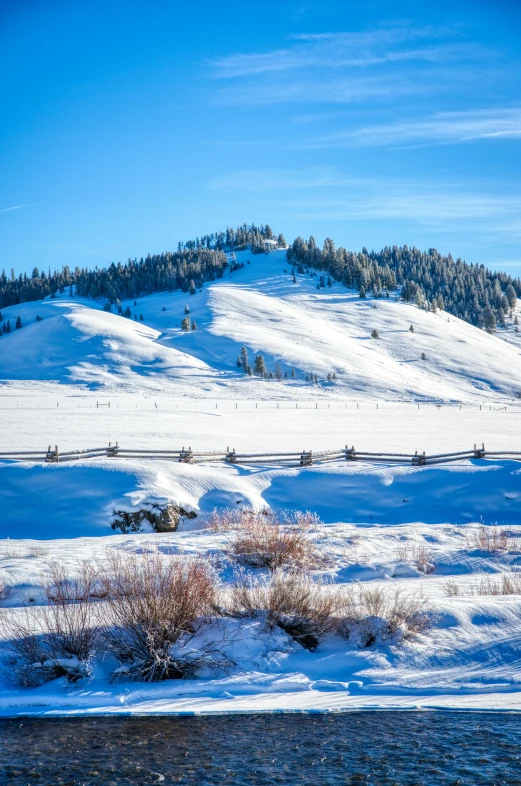 a mountain covered in snow next to a river, trees in the grassy hills, slide show, idaho, high quality picture