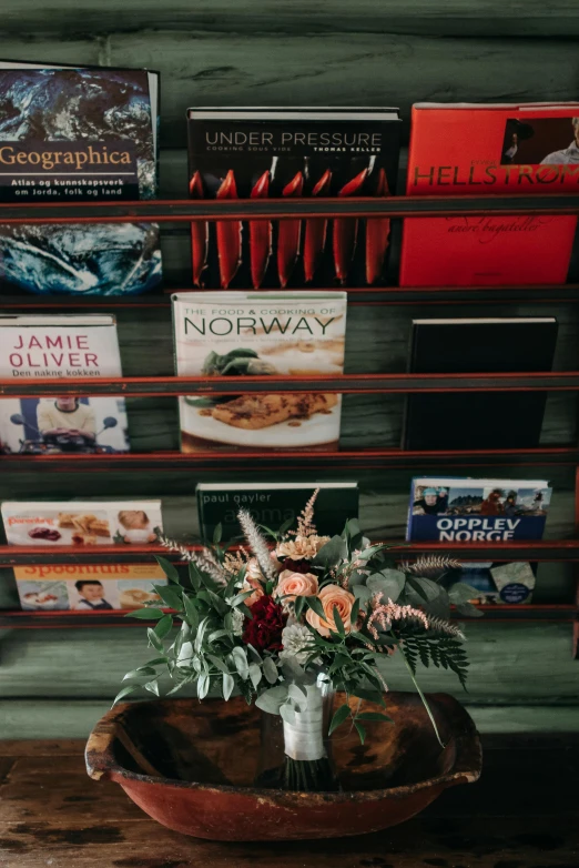 a vase filled with flowers sitting on top of a wooden table, book shelf, commercial, storefront, magazines