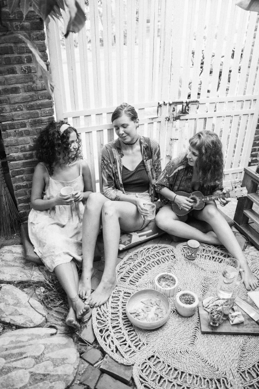 a group of women sitting on top of a rug, a black and white photo, by Eric Peterson, eating outside, trio, kezie demessance, promo image