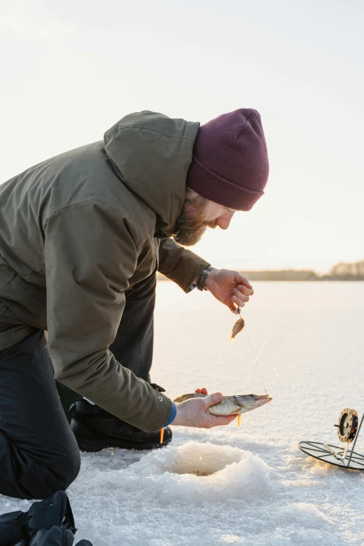 a man that is kneeling down in the snow, by Jesper Knudsen, pexels contest winner, precisionism, holding an fish in his hand, plating, cel shad, anato finnstark and kelogsloops