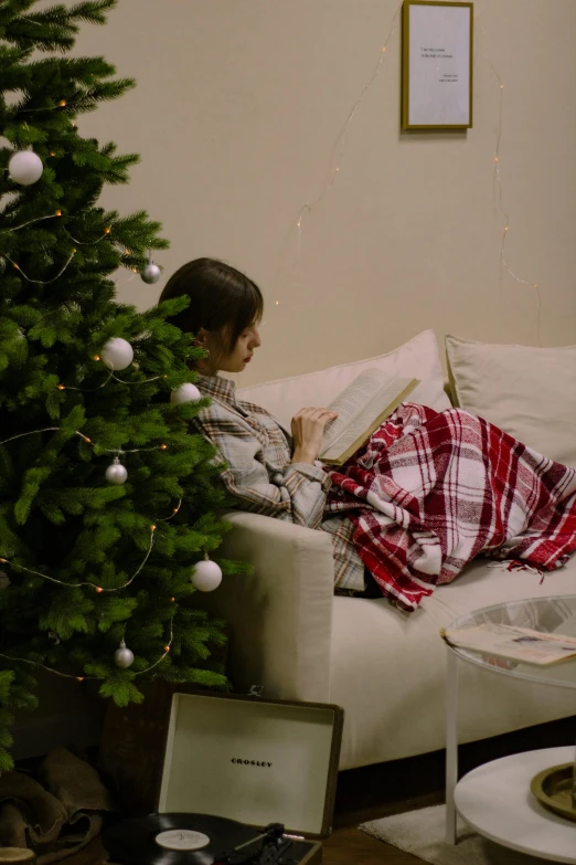 a little boy laying on a couch in front of a christmas tree, a cartoon, pexels, reading the book about love, teenage girl, covered with blanket, gif