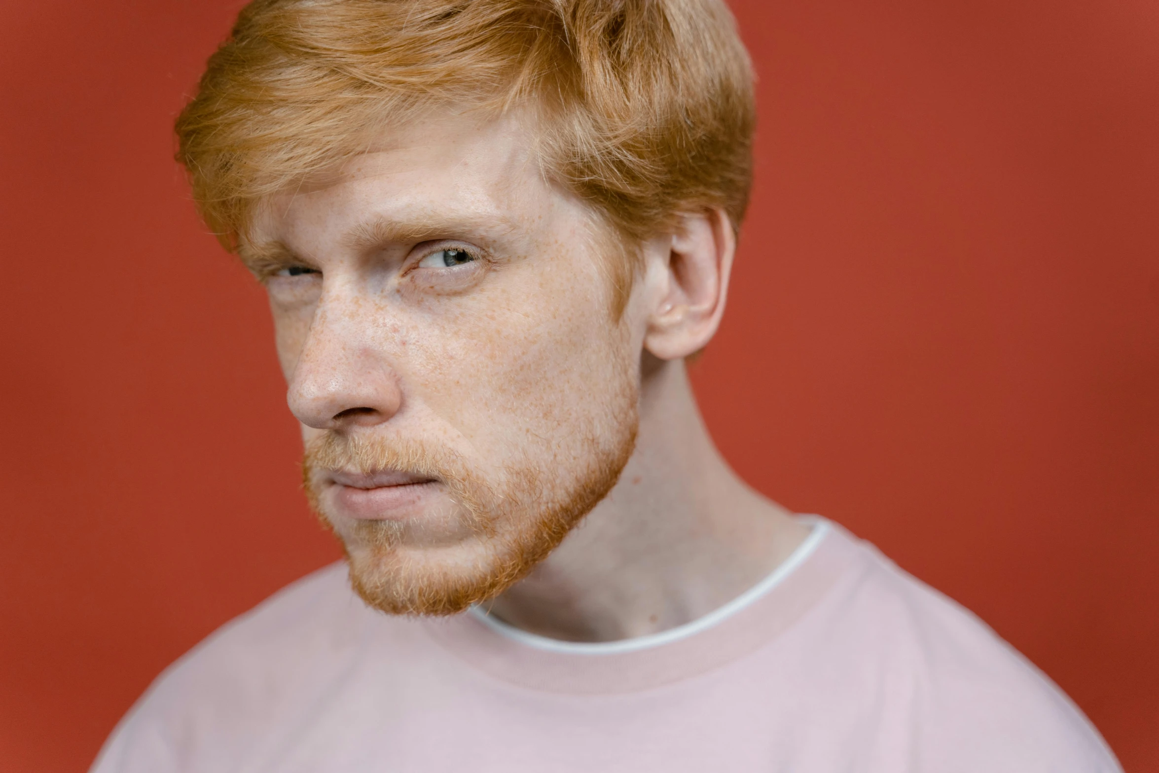 a close up of a person wearing a pink shirt, by Lee Gatch, trending on pexels, hyperrealism, hr ginger, blond brown stubble thin beard, porcelain pale skin, photo for a magazine