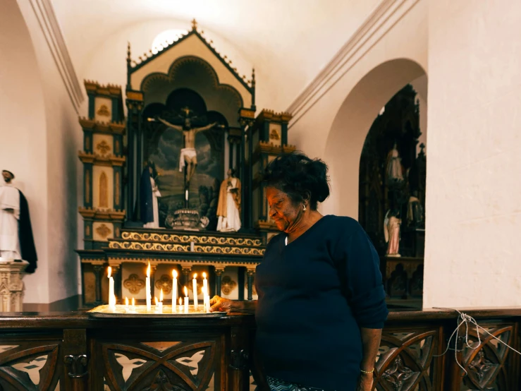 a woman standing in front of a church altar, by Daniel Lieske, pexels contest winner, african american woman, dripping candles, iconostasis in the bar, comforting and familiar