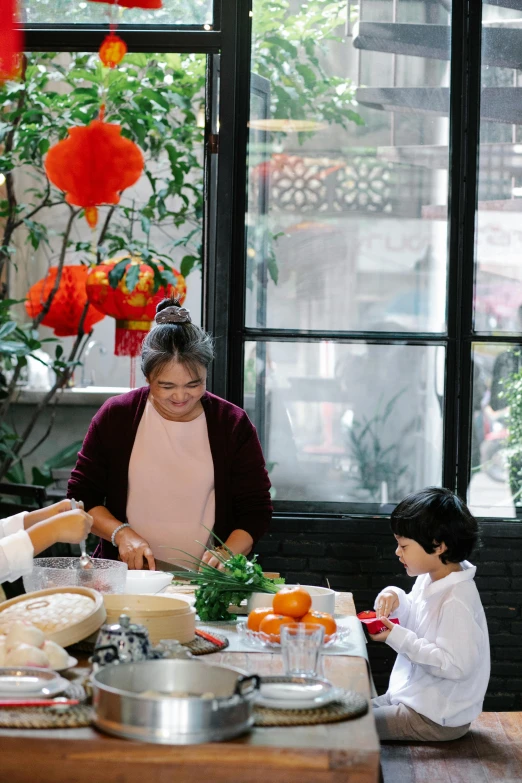 a group of people standing around a table with food on it, with a kid, bao phan, in the kitchen, gif