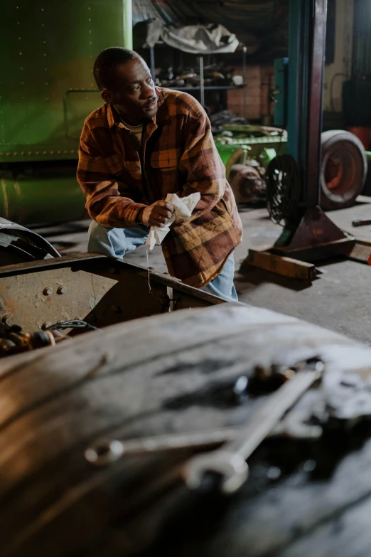 a man working on a piece of wood in a workshop, a portrait, inspired by Raymond Leech, pexels contest winner, rusty vehicles, steel mill, thumbnail, multiple stories