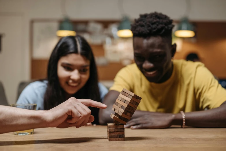 a group of people playing a game of wooden blocks, by Emma Andijewska, pexels contest winner, interactive art, smooth in _ the background, avatar image, riyahd cassiem, close up portrait shot